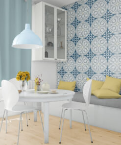 Dining area with white table and chairs, blue pendant light, yellow vase of roses, and a glass-front cabinet against intricately patterned blue wallpaper.