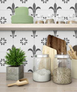 Shelf in a kitchen with glass jars of grains, a tall stack of green plates, cutting boards, a rolling pin, and a plant.