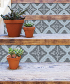 Terracotta pots with succulents on rustic wooden stairs against a blue patterned wall.
