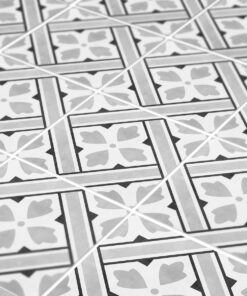 Grayscale close-up of decorative floor tiles with a repeating square pattern and a four-petal floral motif in each tile.