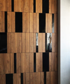 Wooden vertical slat wall with dark rectangular gaps, adjacent to a light gray wall on the right.