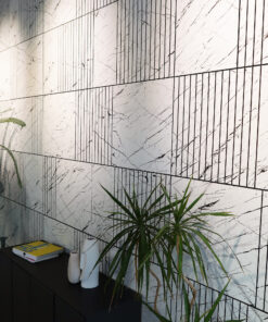 Marble-patterned wall with black grout lines and a dark cabinet below, with a large green plant in front.