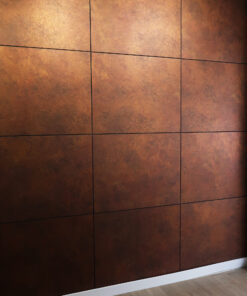 Copper-toned metal wall panels arranged in a grid with dark grout lines, and a white baseboard along the floor edge at the bottom right.