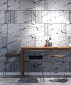 Modern bar area with a marble tiled wall, wooden counter, metal stools, hanging pendant lights, and bottles on the counter.