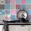 | Casadart | Vinis Autocolantes, Papel de Parede e Painéis Decorativos Stove with a metal kettle and a pan on a black cooktop against a colorful patchwork tile backsplash.