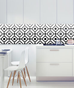 Modern kitchen with a black-and-white geometric tile backsplash, white cabinets, and a white dining table with white chairs and wooden legs.