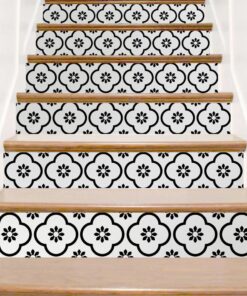 Staircase with decorative black floral tile risers and natural wood treads in a bright space.