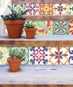 Three terracotta pots with succulents sit on wooden staircase risers covered in colorful patterned tiles.