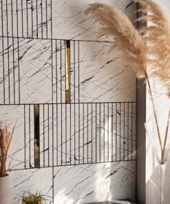 Decorative indoor display: dried pampas grass in a vase against a veined marble wall with a black grid design nearby.