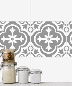 Stack of glass jars with pasta and rice on a tiled kitchen counter against a gray patterned backsplash.