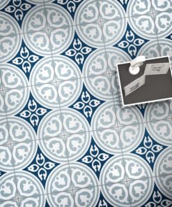 Top-down view of a tiled floor with blue and gray circular medallions; a desk with photos sits in the corner (decorative pattern).