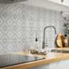 | Casadart | Vinis Autocolantes, Papel de Parede e Painéis Decorativos Gray geometric chevron tile backsplash behind a stainless steel sink and faucet on a wooden counter, with a soap dispenser nearby.