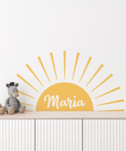 Light-colored nursery with a yellow sunburst wall decal and stuffed giraffe and zebra toys on a wooden dresser.