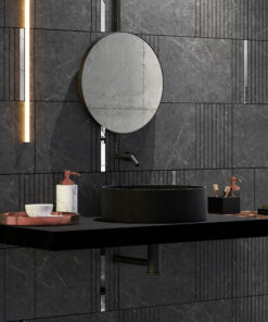 Minimalist bathroom: round concrete mirror above a black vessel sink, set against dark marble walls with linear tile accents.