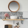 | Casadart | Vinis Autocolantes, Papel de Parede e Painéis Decorativos Round wooden-framed mirror over a white sink with gray patterned tile backsplash and a wooden shelf displaying soaps and bottles.